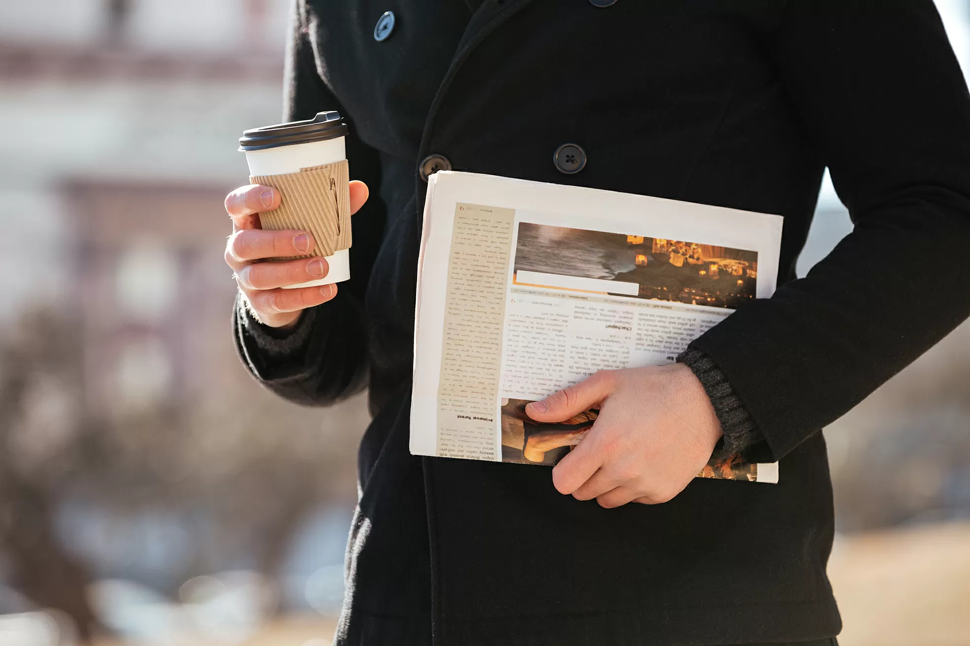 Closeup of man with coffee and newspaper walking in the city